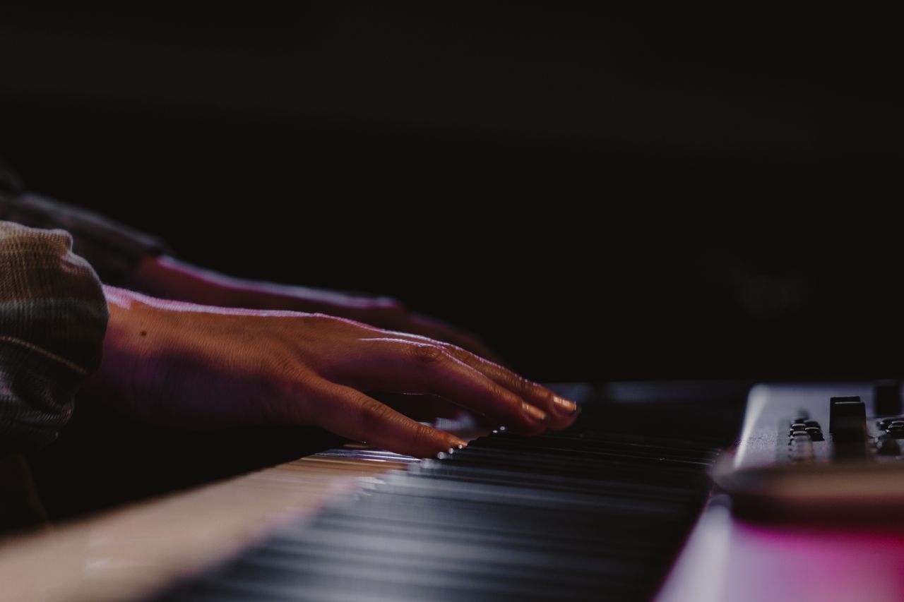 missions-02 Elegant close-up of hands playing a synthesizer keyboard, capturing music and artistry.