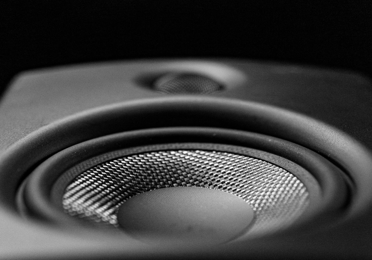 services-03 A detailed black-and-white close-up image of a speaker, highlighting its intricate design.
